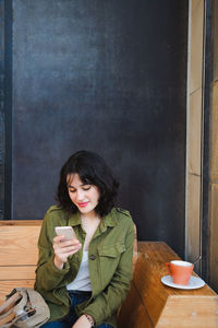 Young woman using phone while sitting at table