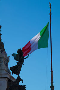 Low angle view of flags against clear blue sky