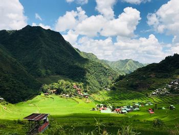 Scenic view of field by mountains against sky