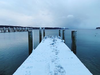 Wooden pier over sea against sky during winter