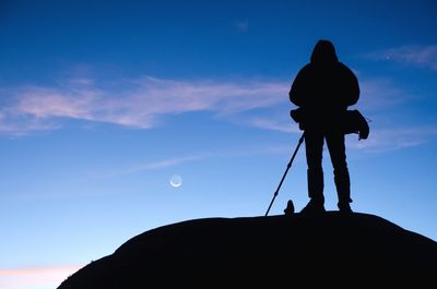 Silhouette photographer against blue sky