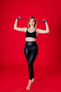 Portrait of a serious young woman against red background