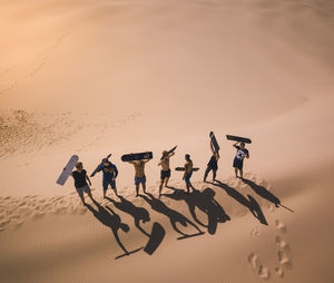 High angle view of male friends carrying surfboard while standing at beach