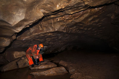 Manual worker cleaning boot while sitting in cave