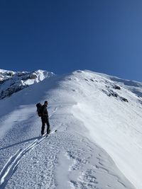 Low angle view of snowcapped mountains against clear blue sky