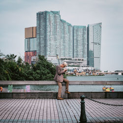 Woman against buildings in city against sky