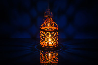 Golden lantern with reflection from blue background for holy month of ramadan kareem.