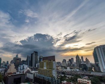 Modern buildings in city against sky during sunset