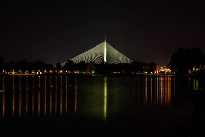 Illuminated calm lake against clear sky at night