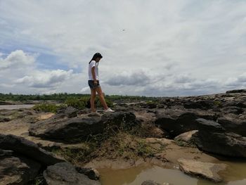 Woman standing on rock against sky