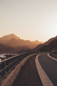 Road leading towards mountains against clear sky