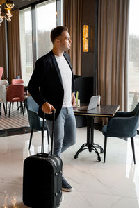 Man with suitcase standing in restaurant