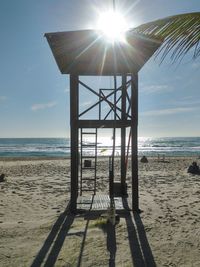 Lifeguard hut on beach against sky on sunny day