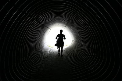 Silhouette of man walking in tunnel