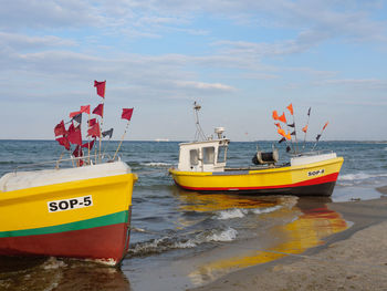 Boats moored on beach against sky
