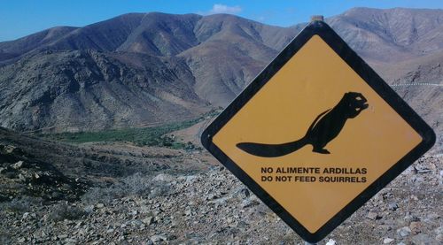 Close-up of road sign against mountain range