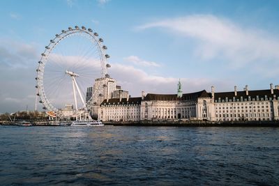 Ferris wheel by river in city