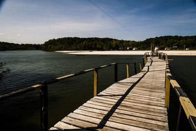 Pier amidst trees against sky