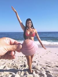 Full length of young woman at beach against clear sky