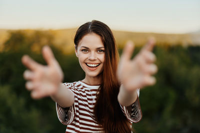 Portrait of young woman standing against trees