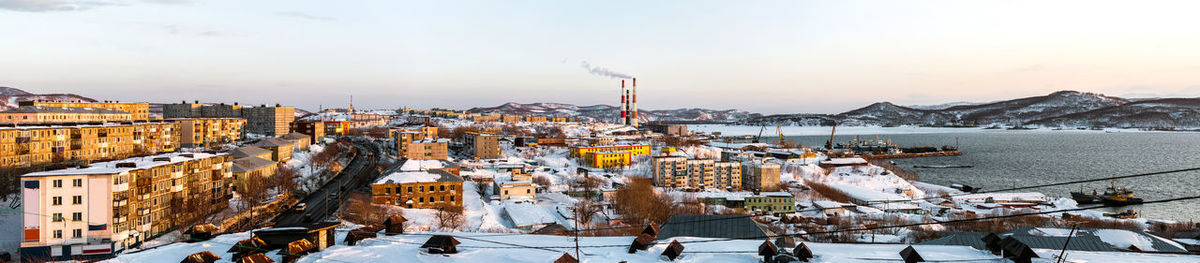 Panoramic view of snowy cityscape against sky