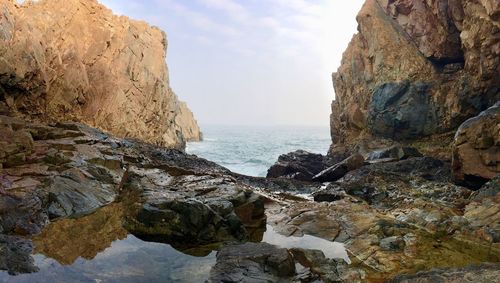 Rock formations by sea against sky