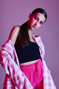 Portrait of young woman standing against gray background