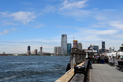 View of buildings by river against cloudy sky