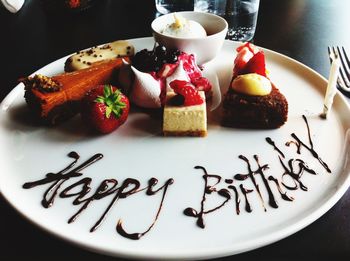 Desserts in plate with happy birthday written with chocolate sauce