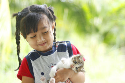 Cute girl holding cat outdoors