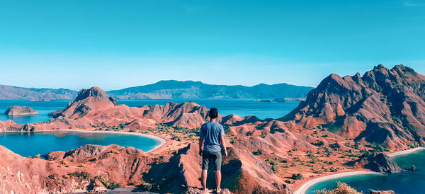 Rear view of people standing on rock against sky