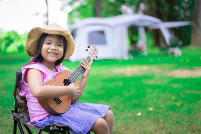 Full length of smiling young woman playing guitar