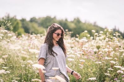 Smiling young woman in sunglasses on field during sunny day