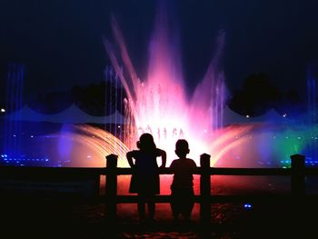 Silhouette of children by fountain at night