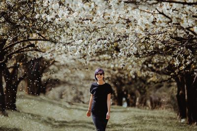 Full length of young woman standing by tree