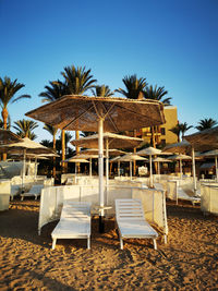 Chairs and tables on beach against clear sky