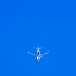 Low angle view of airplane flying against clear blue sky