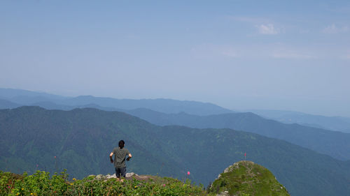 Rear view of man looking at mountains against sky