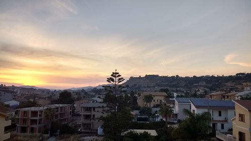 Houses in town against sky during sunset