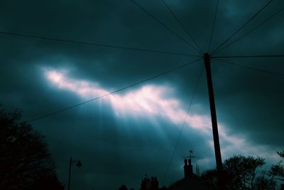 Low angle view of silhouette electricity pylon against sky