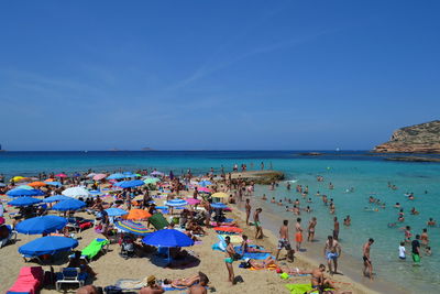 Panoramic view of people on beach against clear blue sky