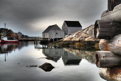 Houses by lake and buildings against sky