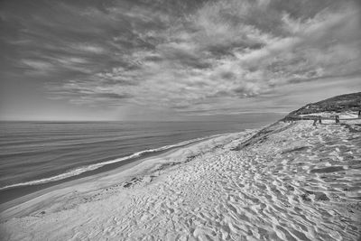 Scenic view of beach against cloudy sky