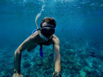 Man swimming in sea against blue sky