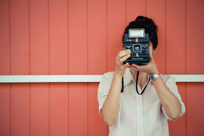 Woman photographing against wall