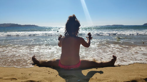 Rear view of woman on beach against sky