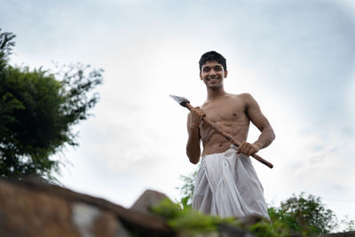 Low angle view of shirtless man standing against sky