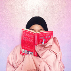 Midsection of woman holding book against wall