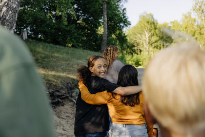 Portrait of smiling girl walking with arm around female friend at summer camp