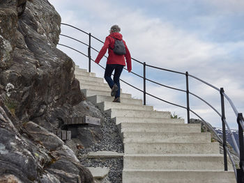 Low angle view of woman climbing on steps against sky